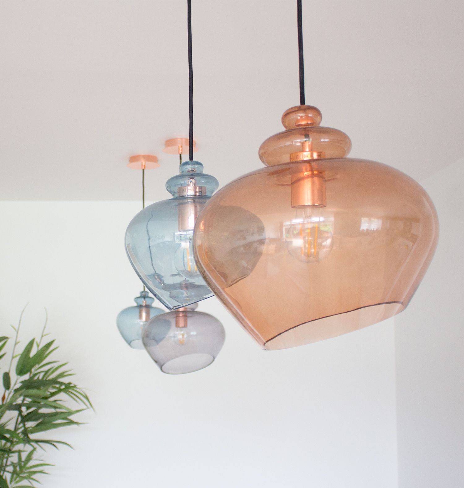 A close up of the four glass blown pendant lights in orange and blue.