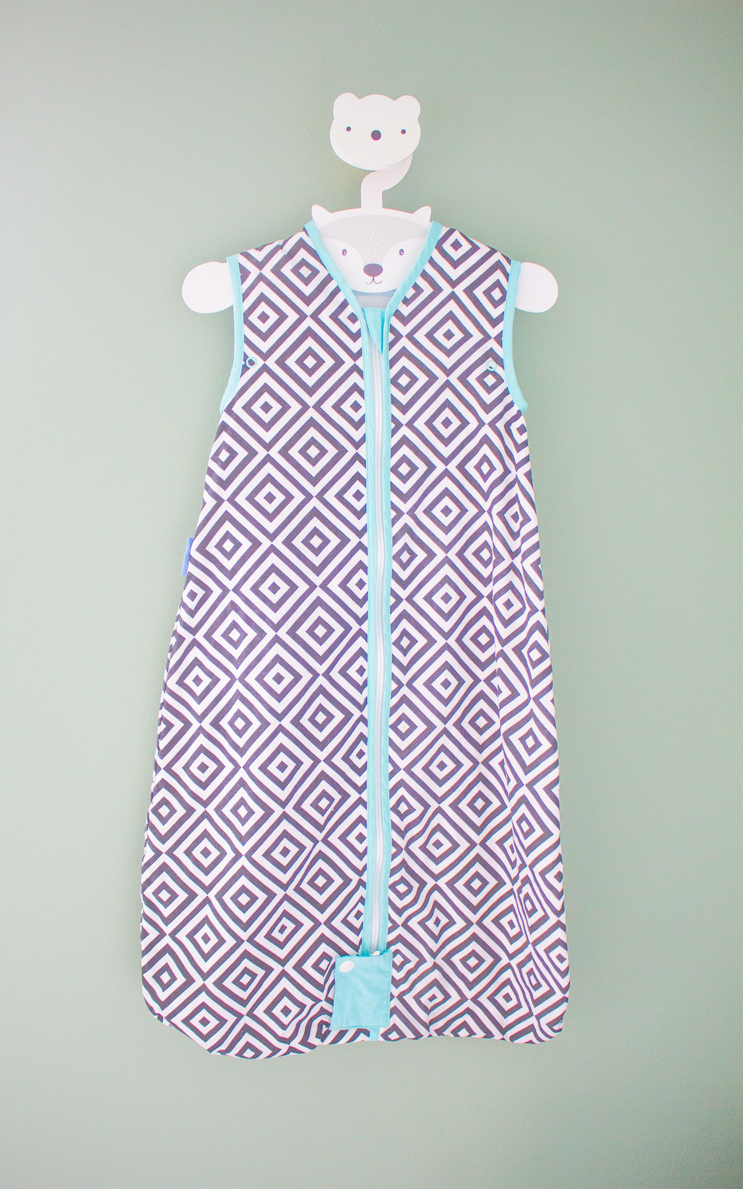 A close up a black and white baby sleeping bag hanging on a white hook.