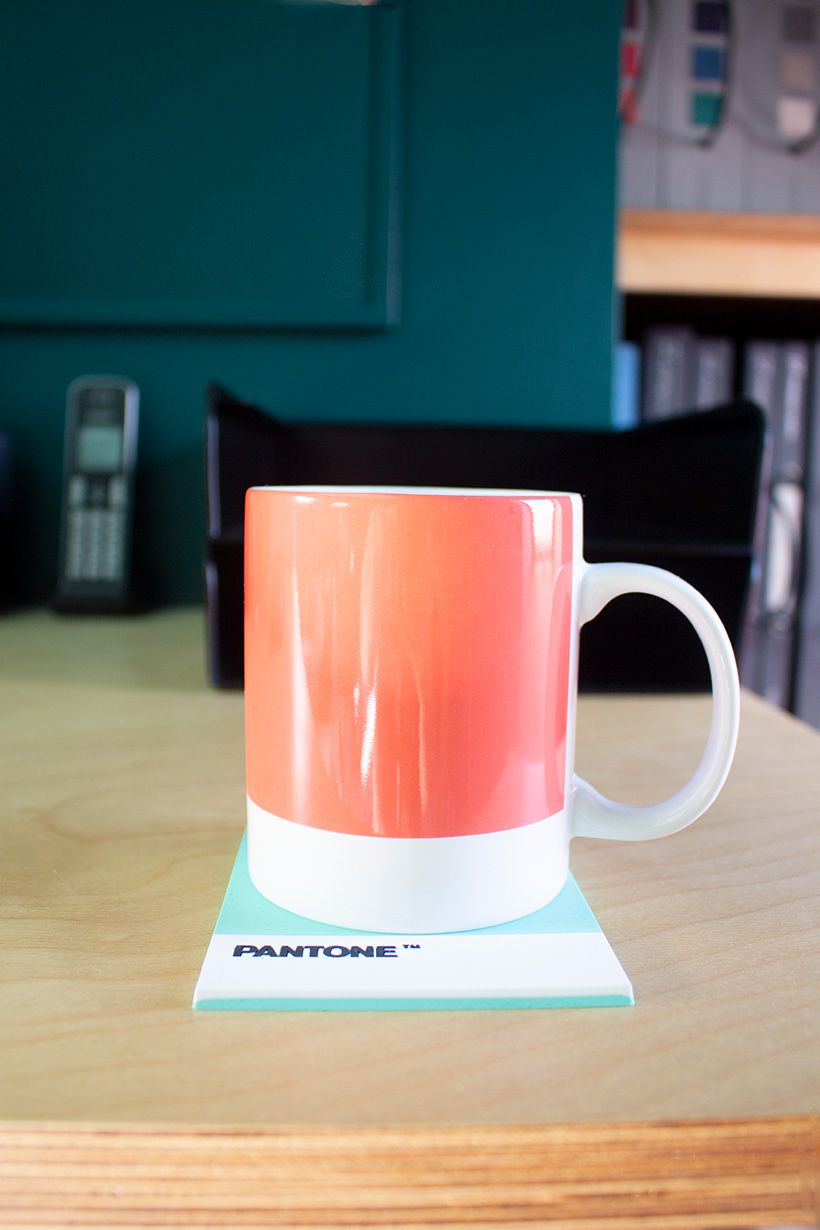 A close up of an orange mug on the desk.