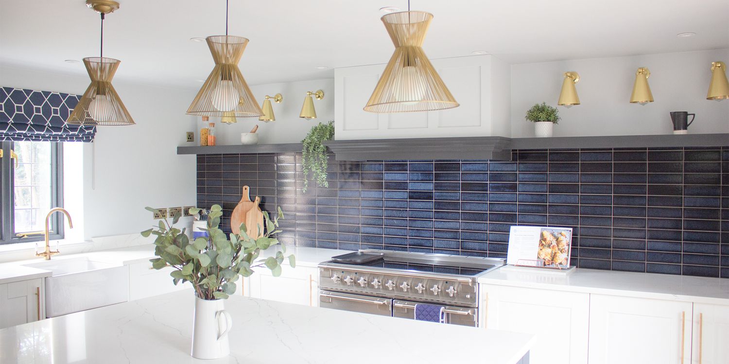 A photo of the navy tiles, marble worktop and brass lights in the new kitchen.