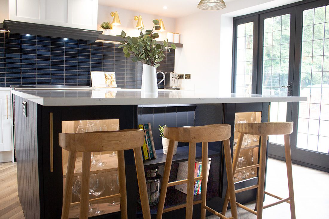 A photo of the navy kitchen island with the wooden bar stools underneath.