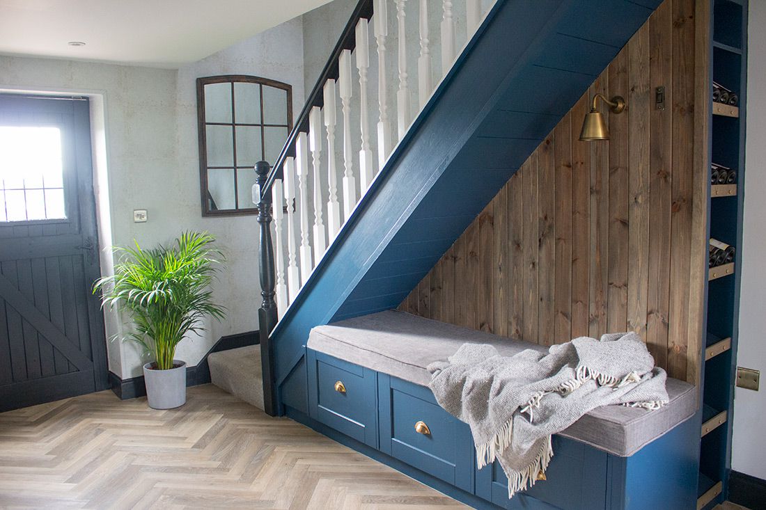 A photo of the hallway, with dark blue painted under stairs seating and storage.