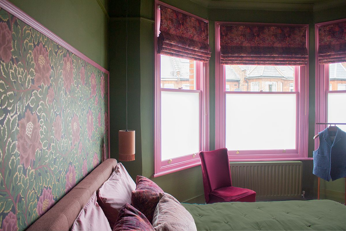 A photo looking along the headboard with pink floral wallpaper behind the bed.