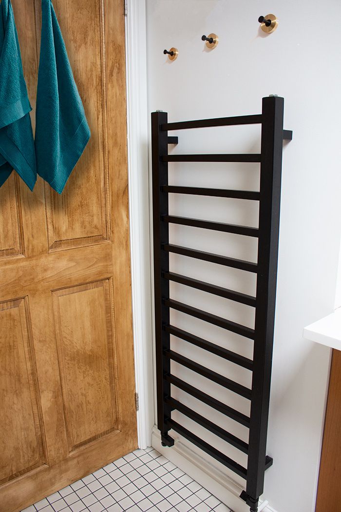 A photo of the new black radiator on the wall, with hooks above it..