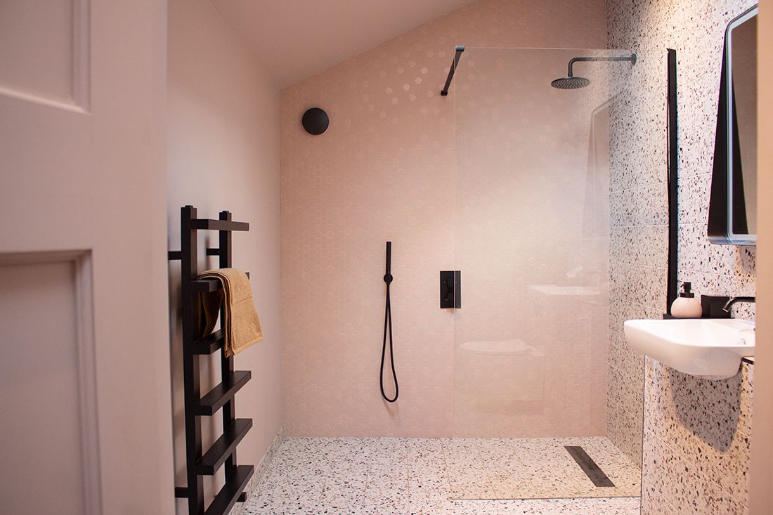 The new wet room, with black fittings and pink hexagonal tiles on the wall.