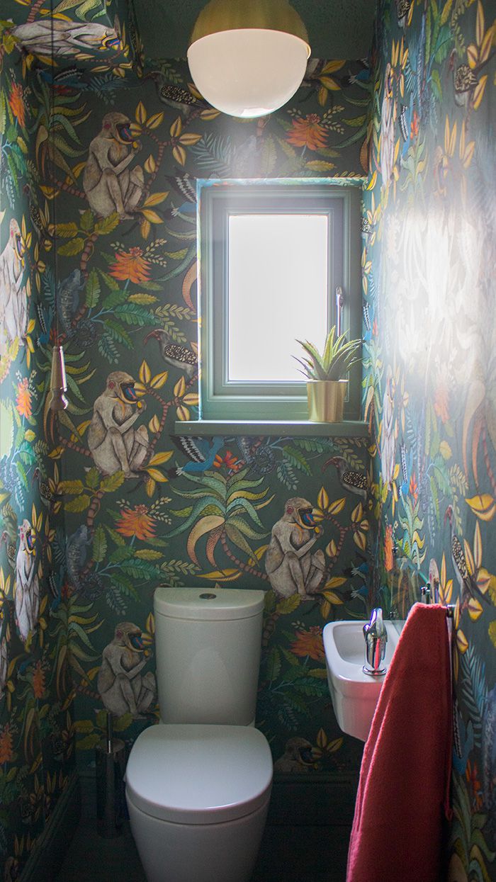 A photo of the upstairs WC, with colourful Cole & Son wallpaper and brass fittings.