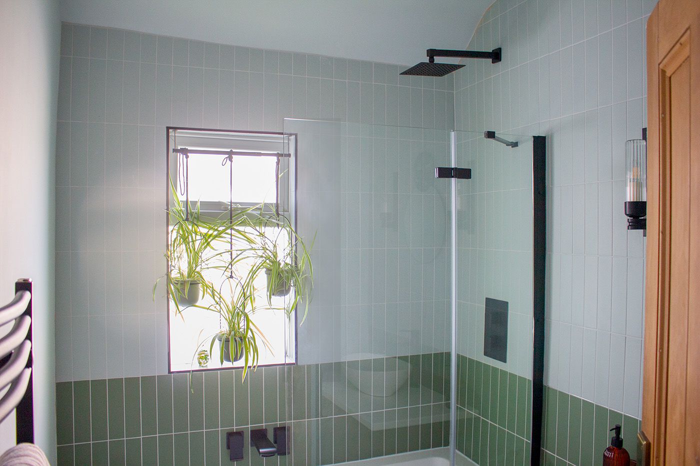 The refreshed main bathroom with new sanitary ware, a vintage dresser as a sink, and green and pink tiling.