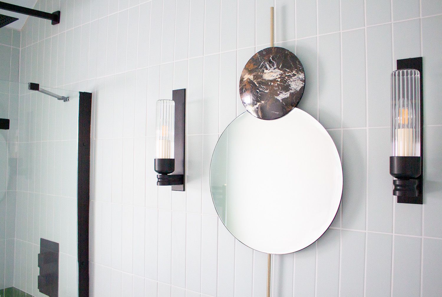 A close up of the main bathroom mirror, which has black marble and brass details.