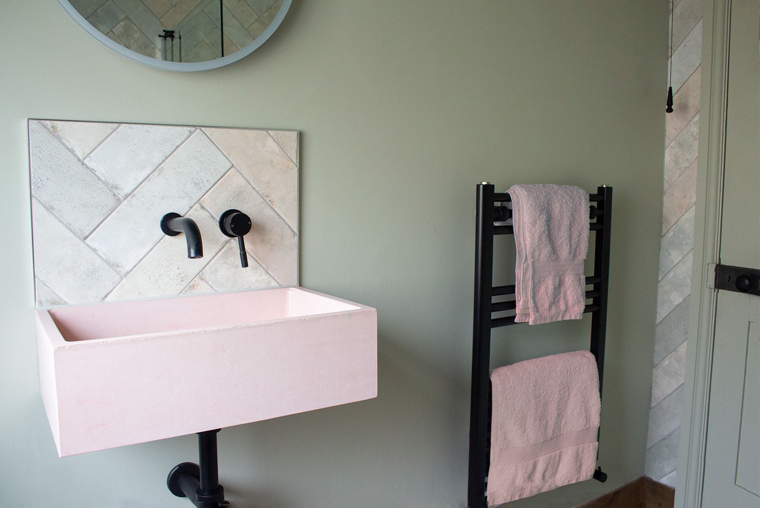 A photo of the pink concrete sink and new black radiator in the en suite.