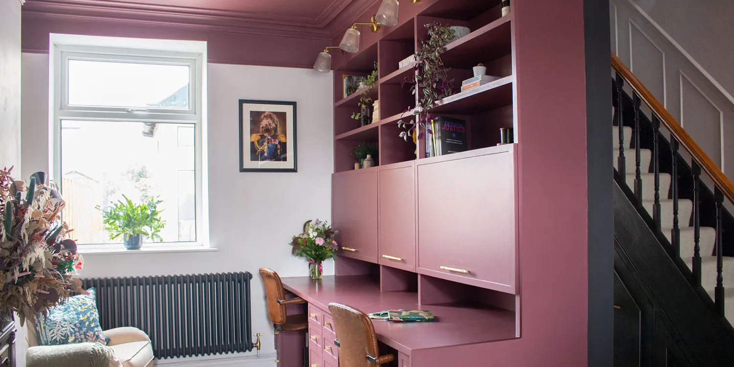 A photo showing the burgundy double desk with period cornicing and doors which hide the computer screens.
