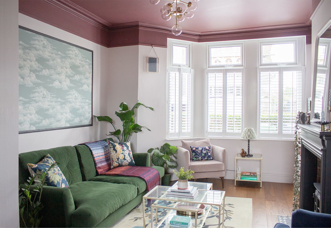 A photo showing the other side of the room to the desk, with a green velvet sofa and glass coffee table.