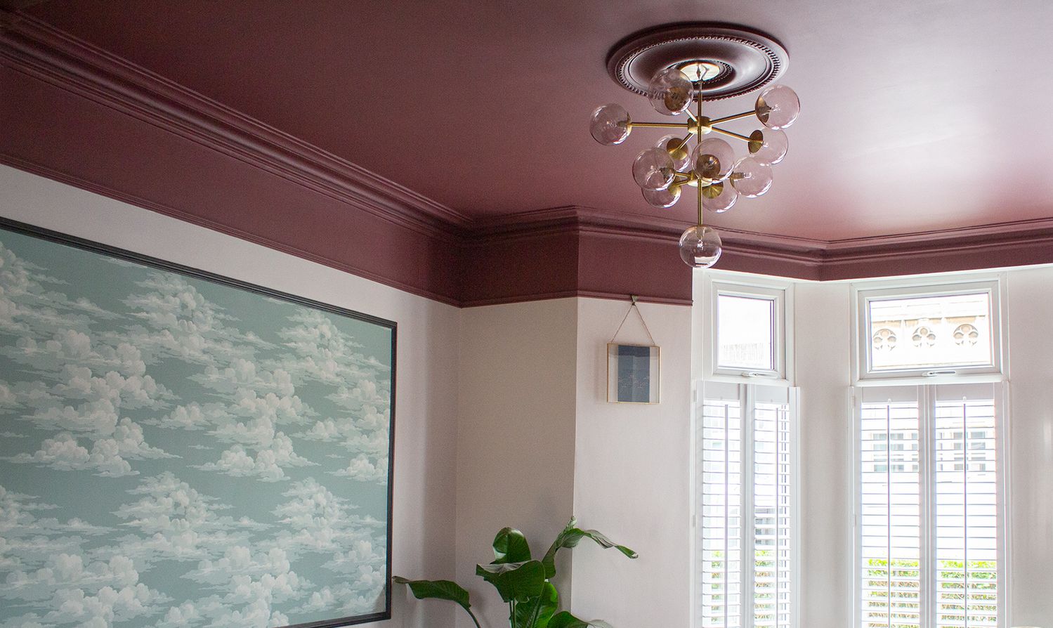 A photo showing the brass and glass ceiling light against the burgundy painted ceiling.
