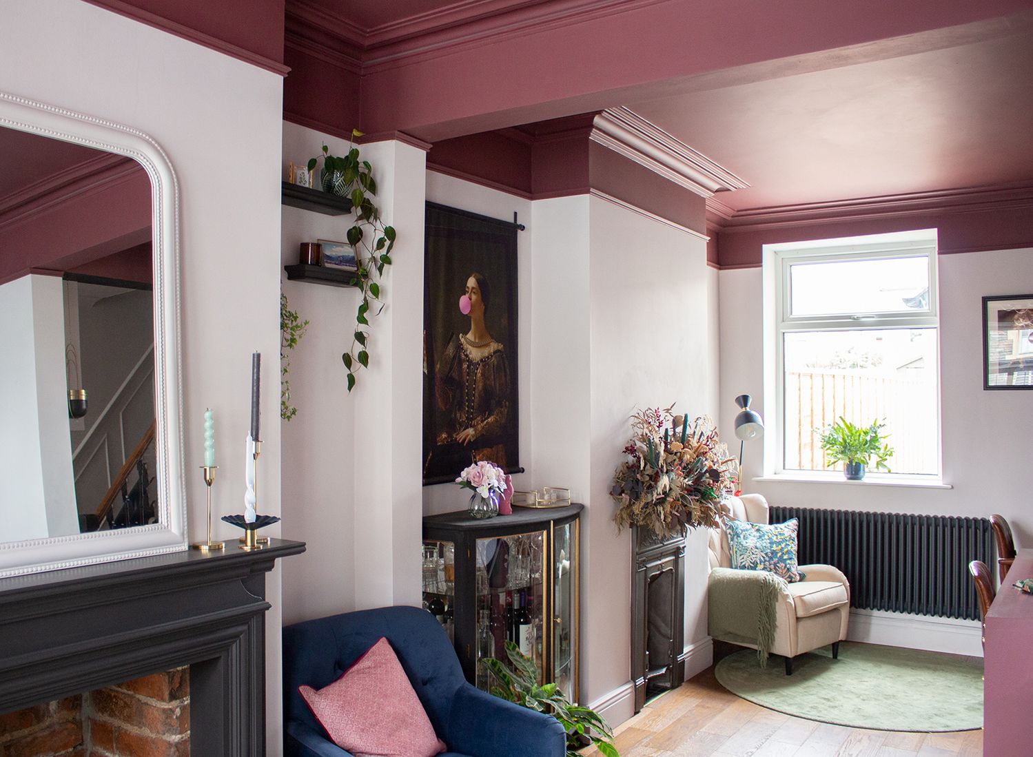 A photo showing the two chimney breasts and fireplaces in the room, with the pale pink walls and burgundy ceiling.