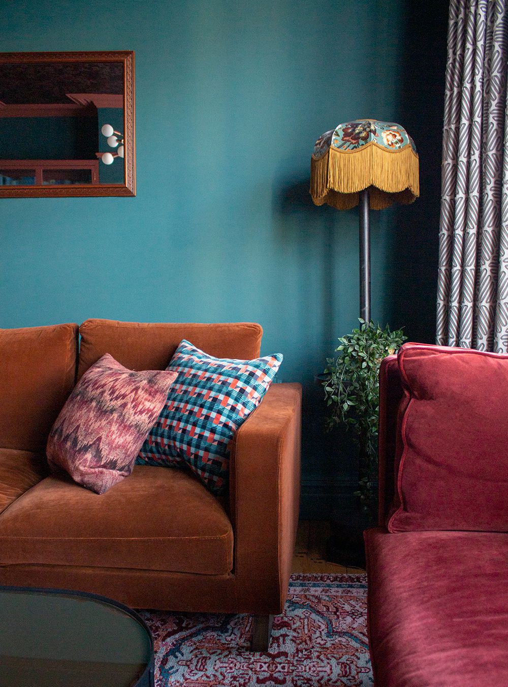 A close up of the floor lamp with a velvet fringed lampshade in the corner of the room.