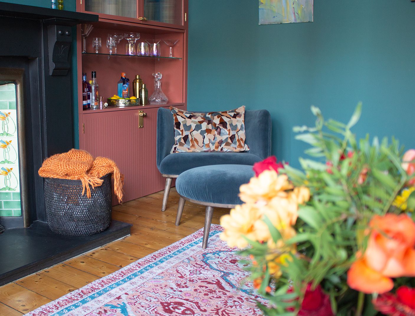 A photo showing the blue velvet chair and matching footstool in front of the cabinet's bar area.