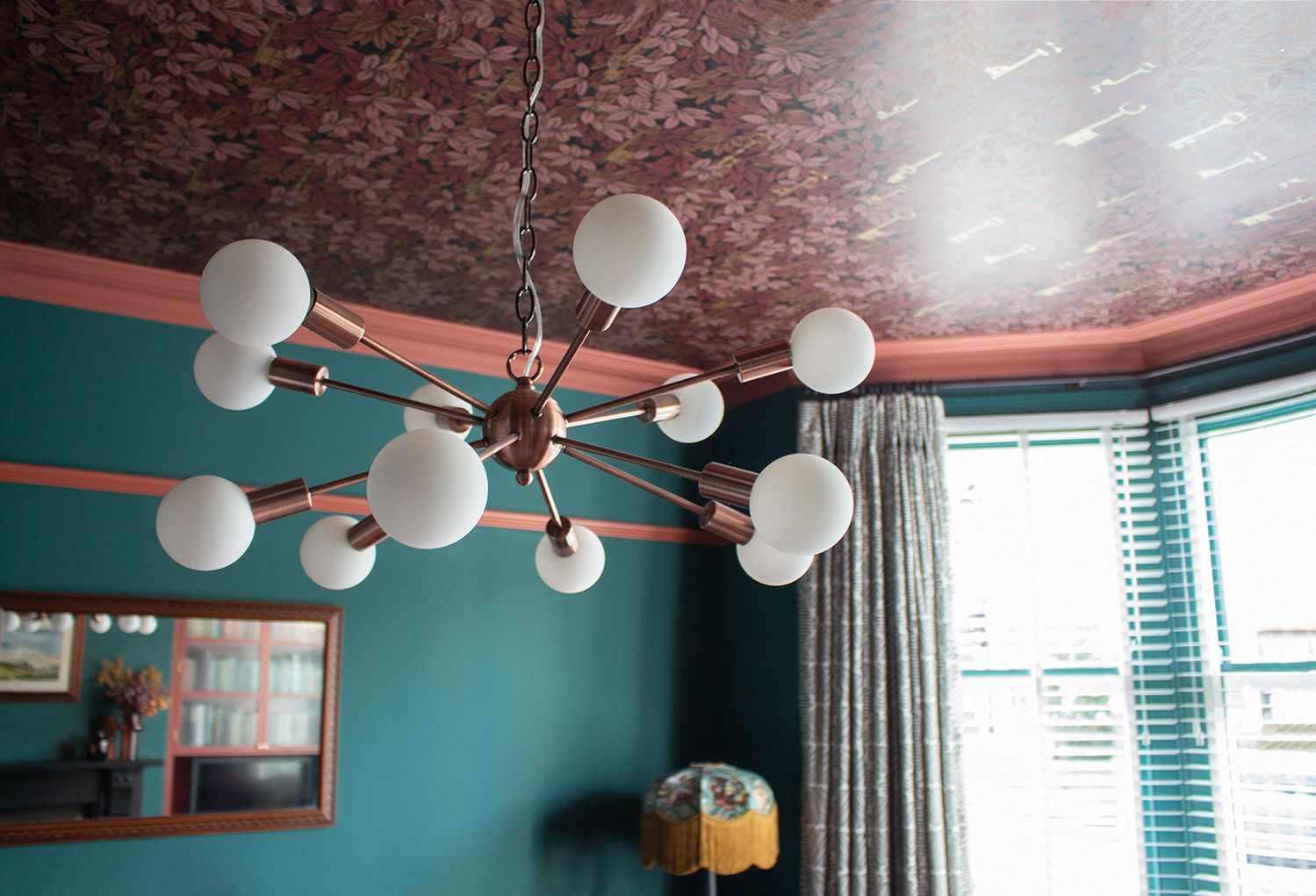A photo showing the sputnik ceiling light with white globe bulbs, with the wallpapered ceiling above.