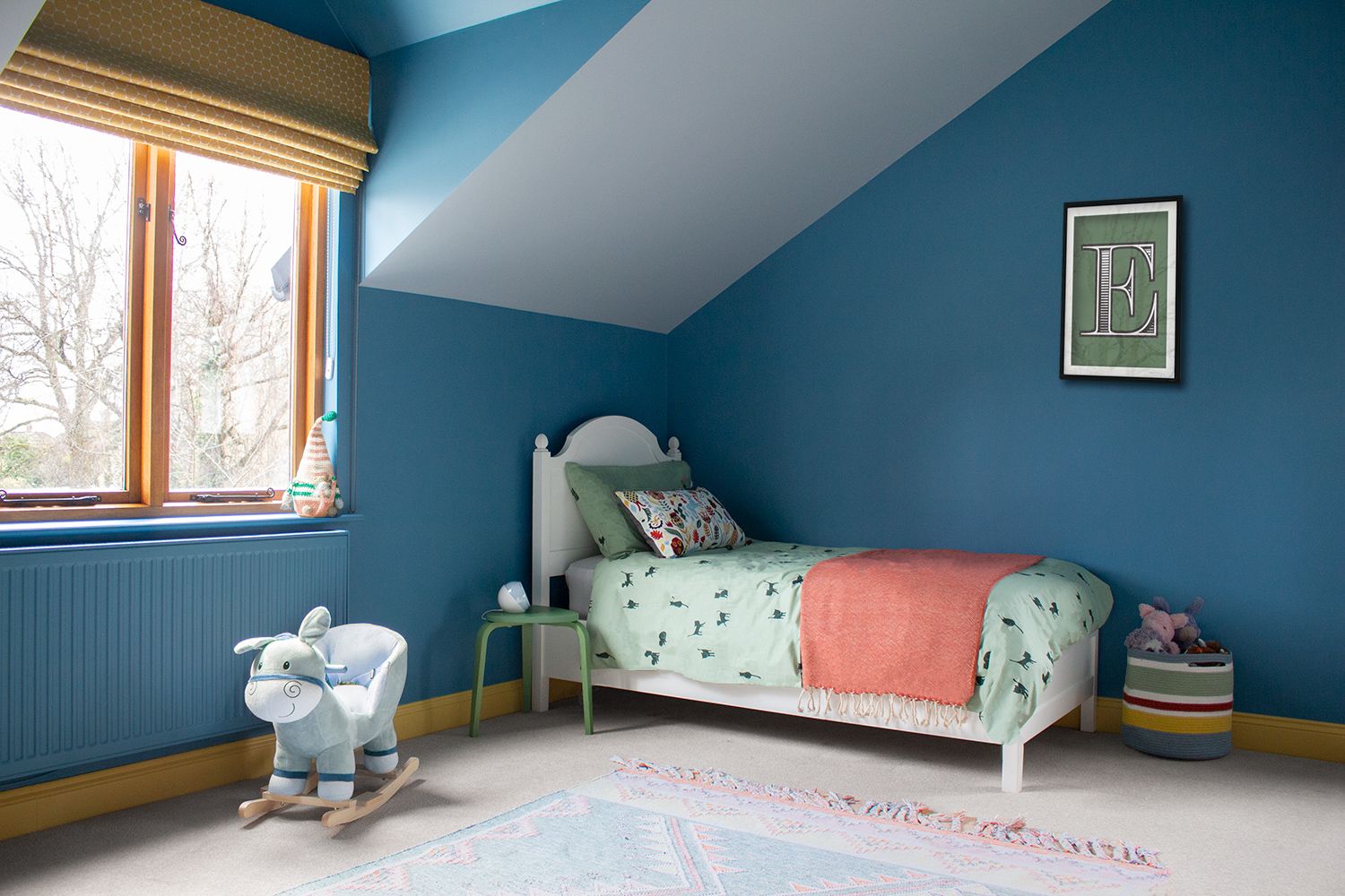 A photo of a child's bedroom showing the blue walls and the bed in the corner.