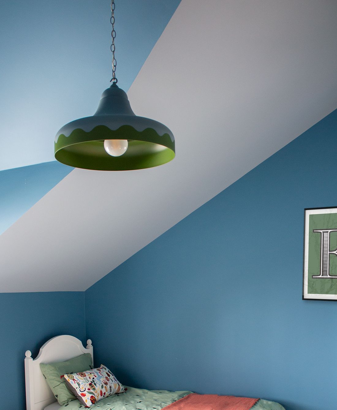 A photo of a child's bedroom showing blue walls with yellow accents, focused on the green and blue pendant light.