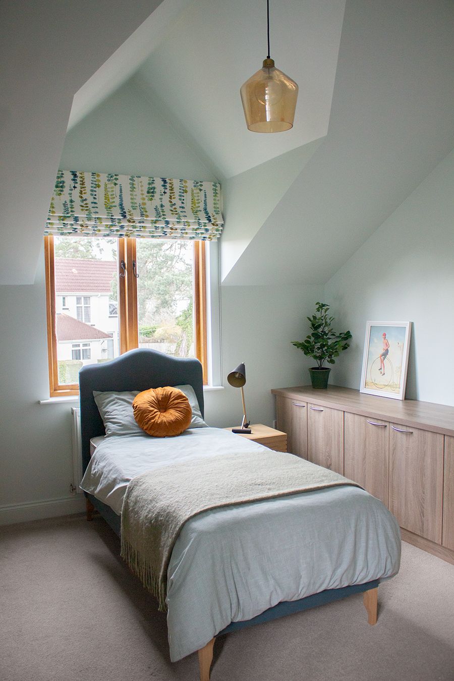 A photo of a child's bedroom which has soft blue walls and a deep aqua bed.