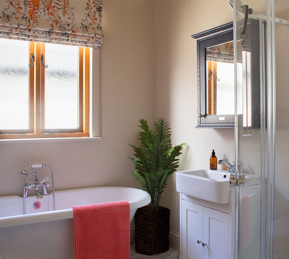 A photo of the family bathroom with warm clay coloured walls and a blue bathroom cabinet.