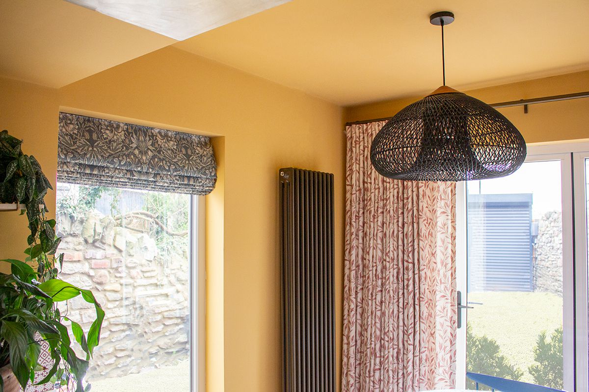 A close up photo showing the single curtain made from a red botanical patterned fabric over the bifold doors.