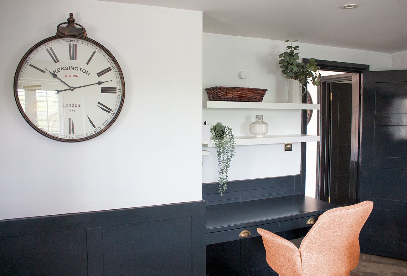 A photo of the paneling and built in desk in the snug, with shelving above and an orange chair.