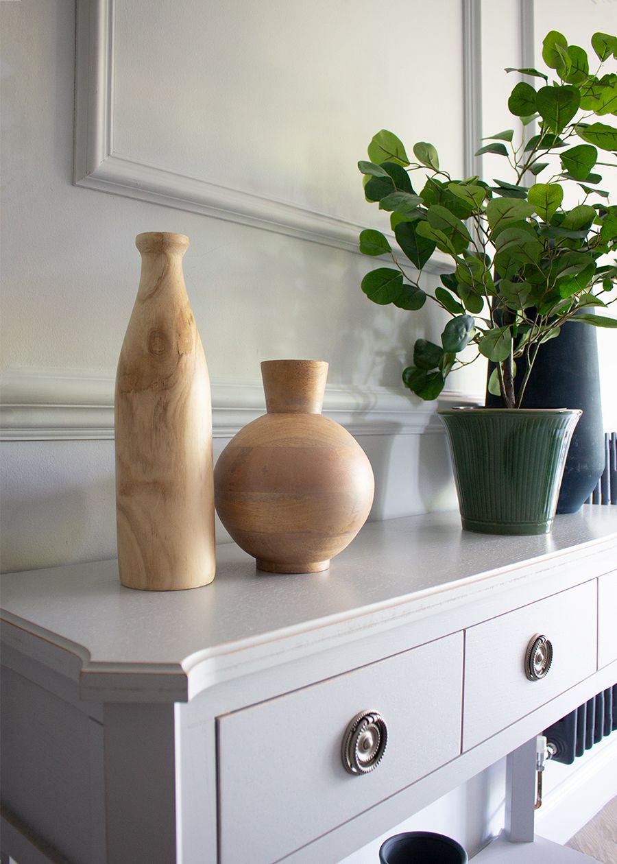 A close up of vases and plants on the console table in the living room.