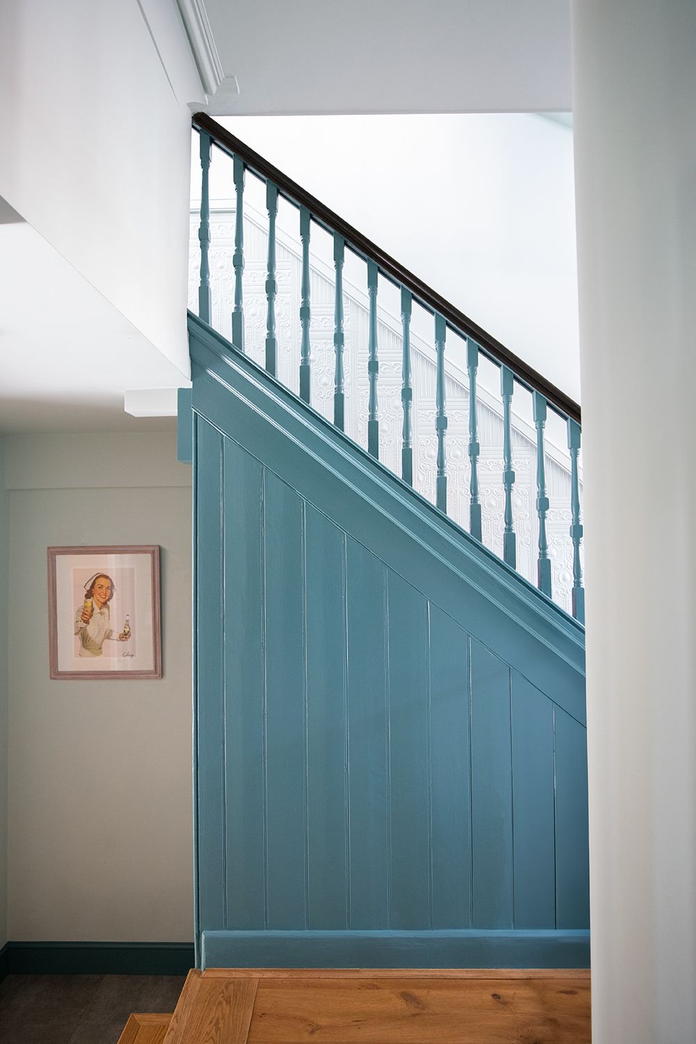 A photo of the side of the stairs in the hallway, which are painted a mid blue.