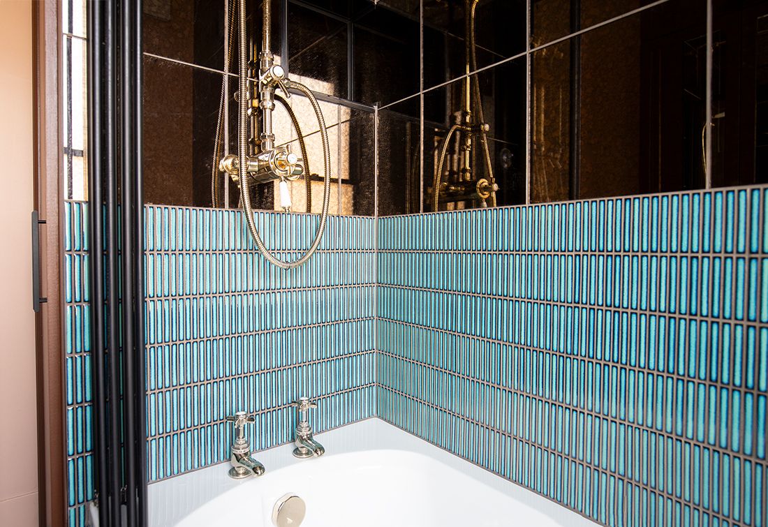 A photo of the bathroom showing the blue finger mosiac tiles in the shower with antiqued mirror tiles above.