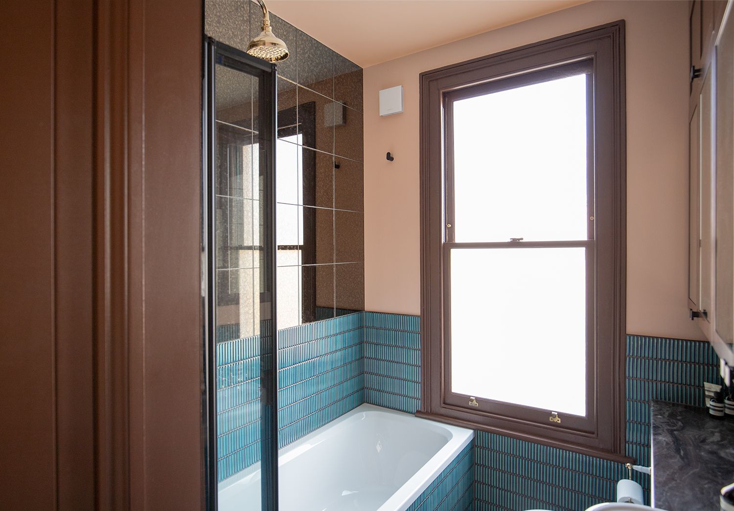 A photo of the bathroom showing the pink walls, brown woodwork and blue tiles.