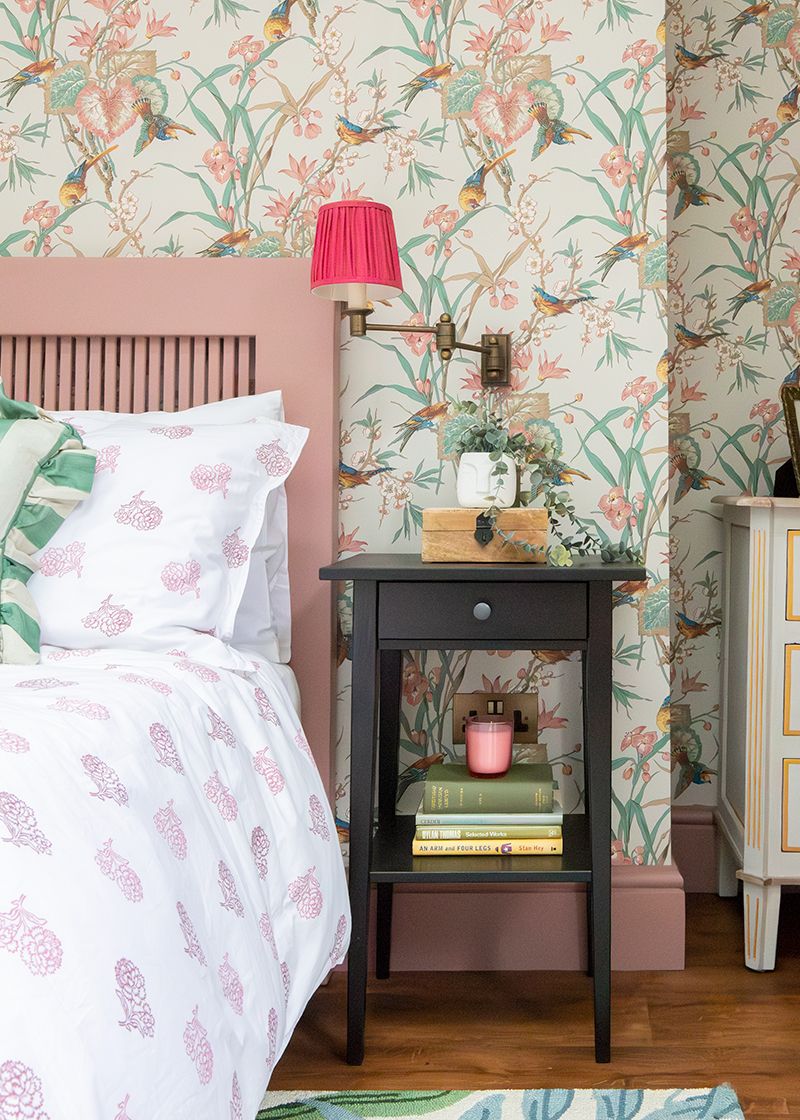 A photo looking along the side of the bed towards the bedside table, showing the reading lamp and items on the table.