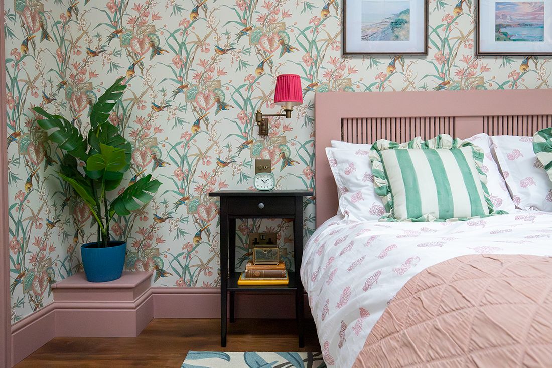 A photo looking along the side of the bed with a dark wooden bedside table next to it.