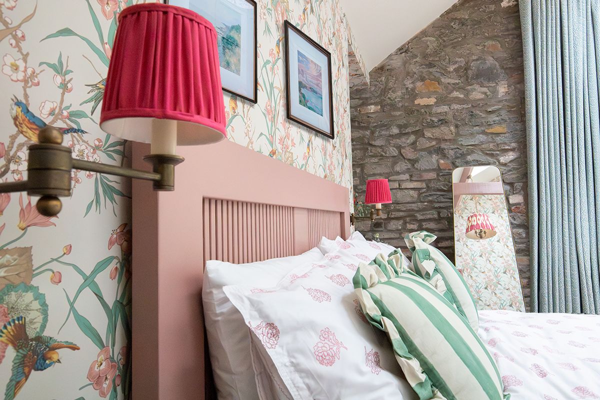 A photo looking along the pink painted headboard of the bed, showing the rasbperry pink wall lights.