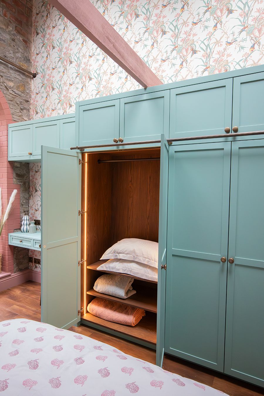 A photo of the wardrobe doors which are open. Inside you can see the dark wood interior and LED lighting along the inside of the storage.