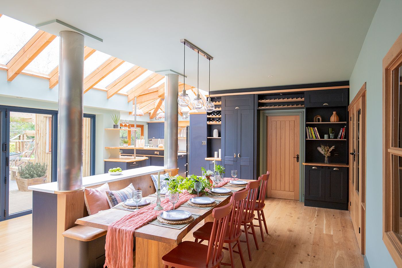 A photo showing a navy blue kitchen with a bespoke waney edge dining table in the centre, with banquette seating.