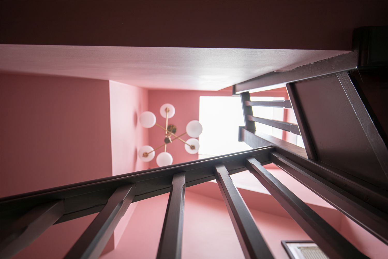 A photo looking up through a stairwell towards a modern light fitting