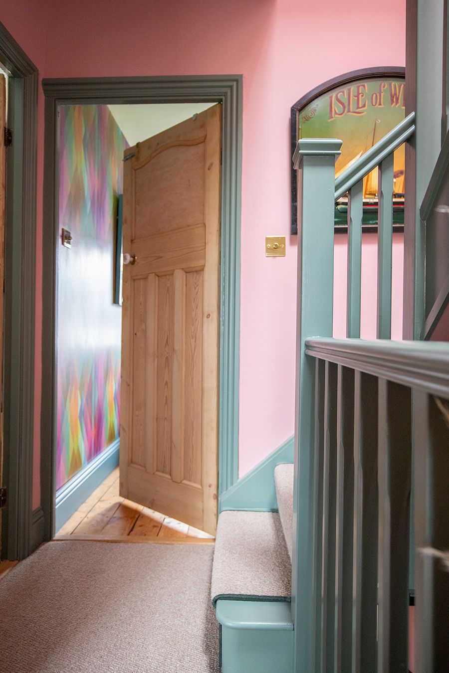 A photo showing a pink landing and sage green staircase