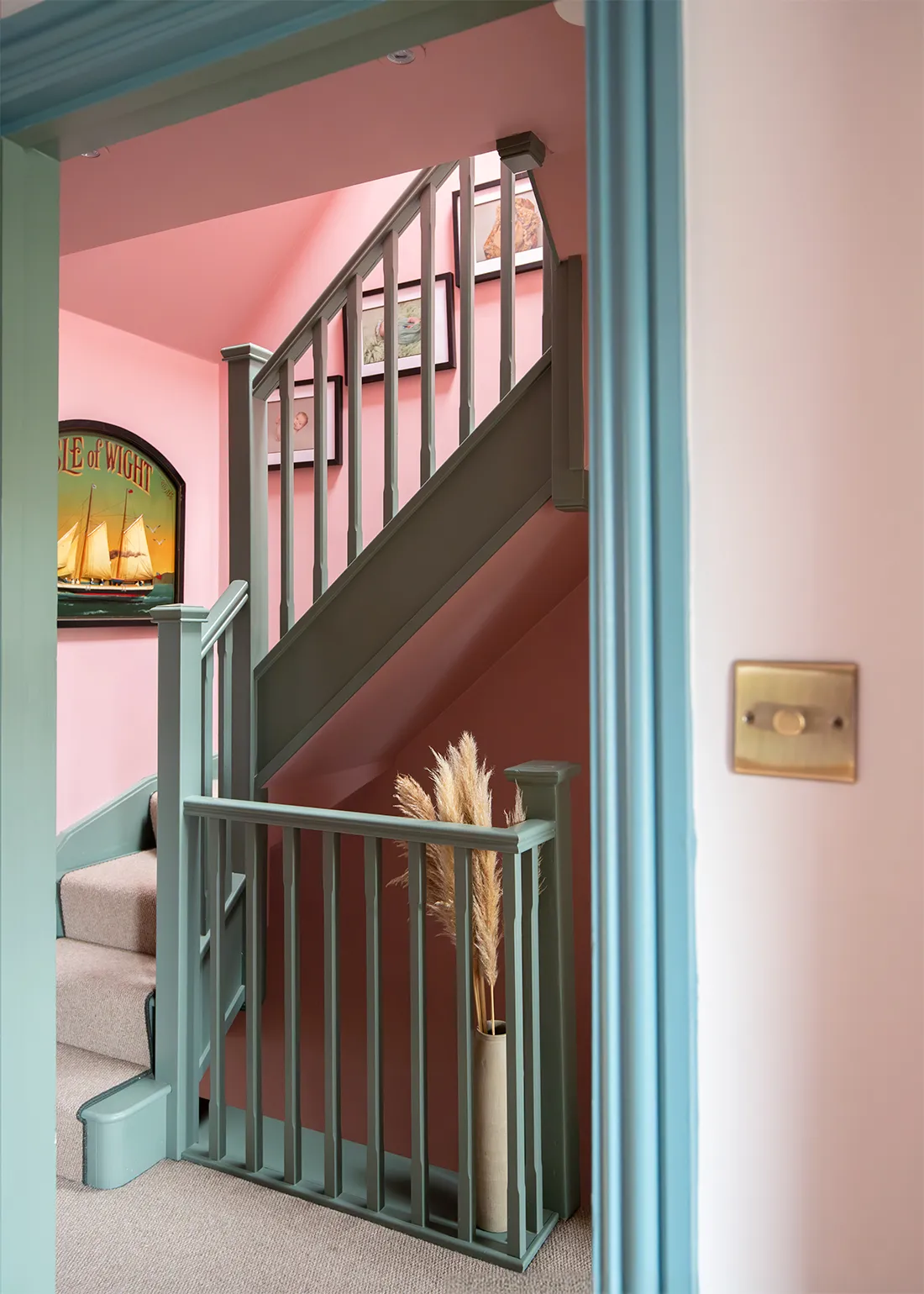 A photo looking through a doorway to a pink landing with green stairs