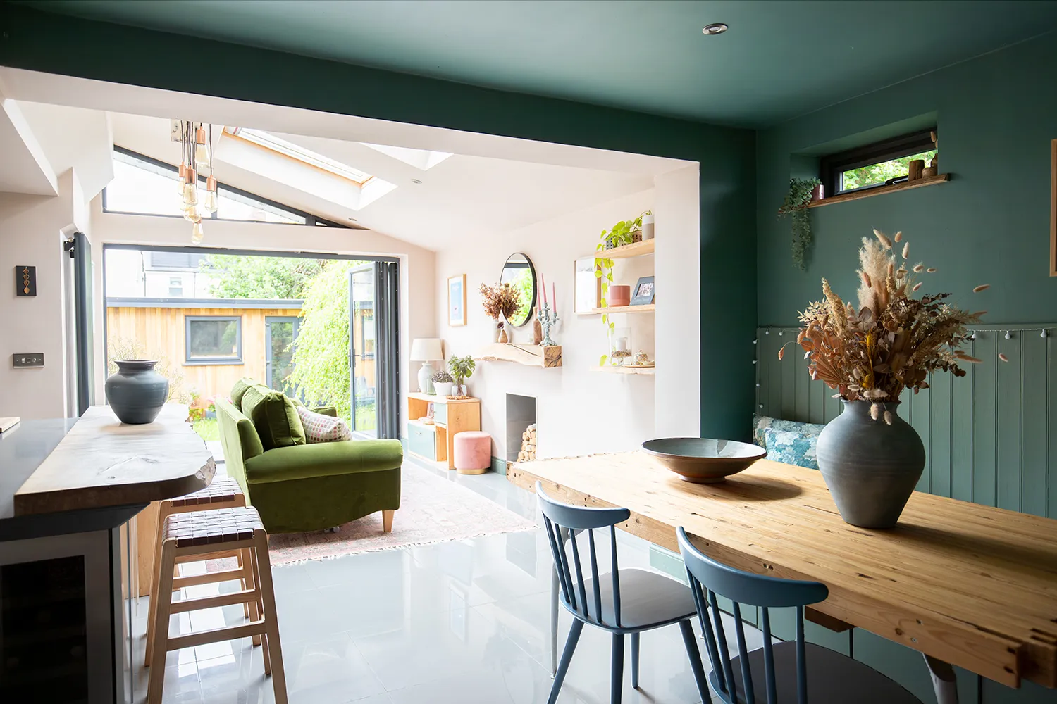 A photo showing a open plan kitchen living space with green sofa