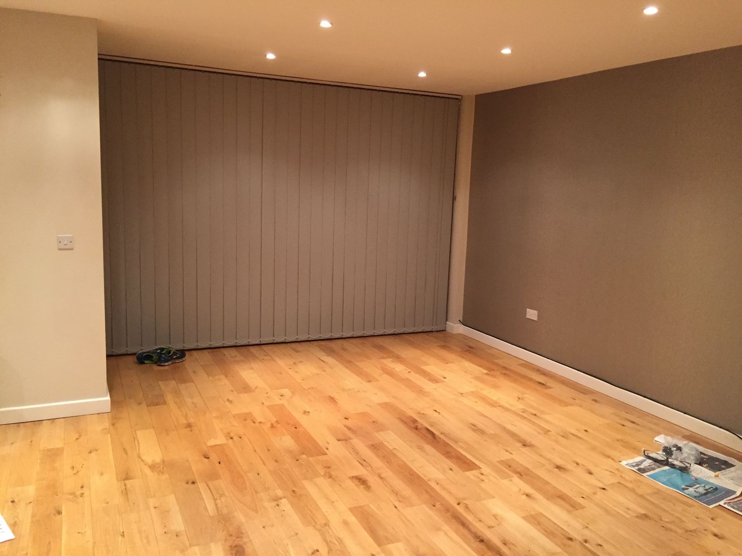 The before photo shows the empty room with a brown painted feature wall and beige walls.