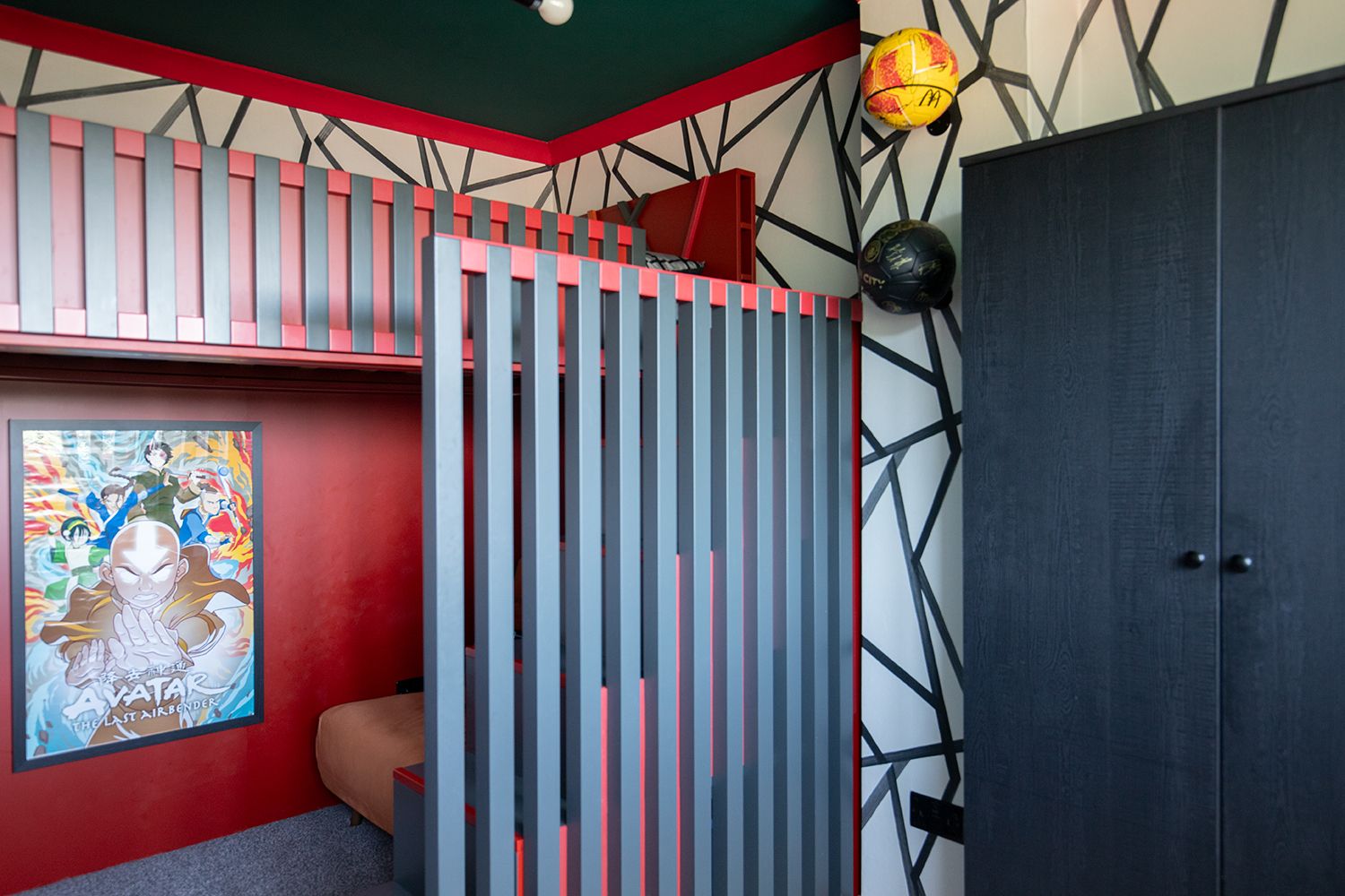 A photo showing the side of the cabin bed with dark grey and red slats along the side of the steps.