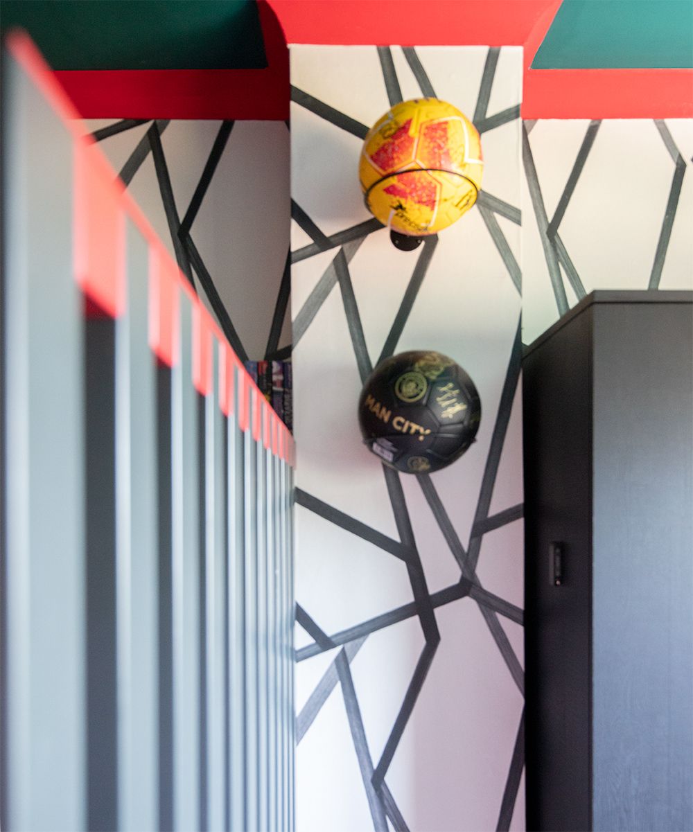 A close up of two cherished signed footballs hung on hoops on a wall.