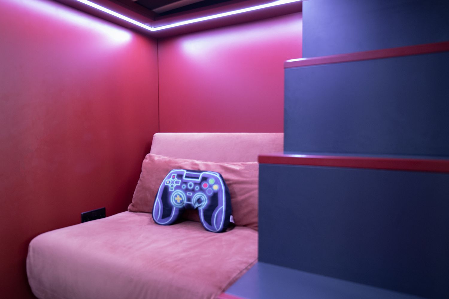 A photo showing the underneath of the cabin bed lit up by LEDs. You can also see the gaming chair.
