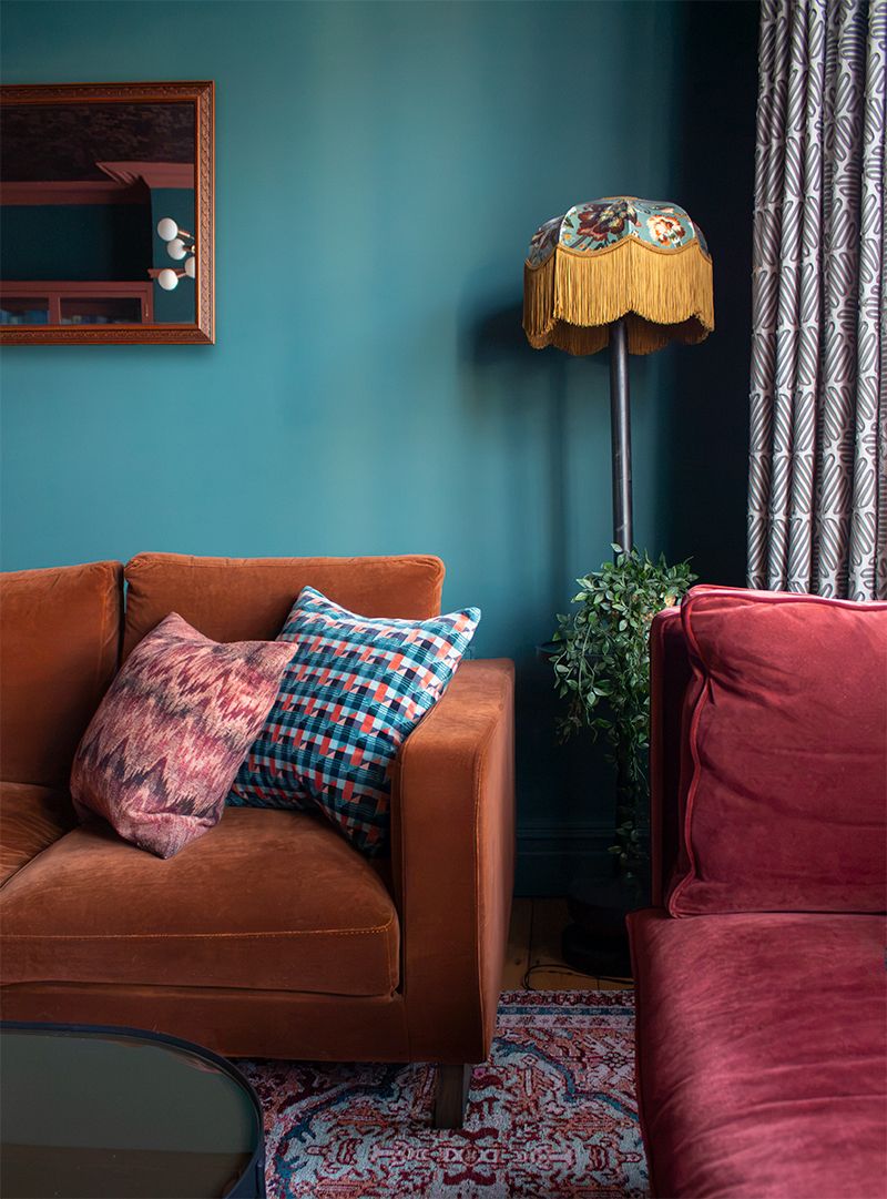 A close up of the floor lamp with a velvet fringed lampshade in the corner of the room.