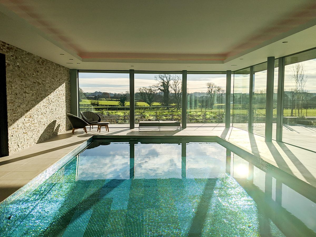 A photo looking down the length of the pool to the glazing and fields beyond.