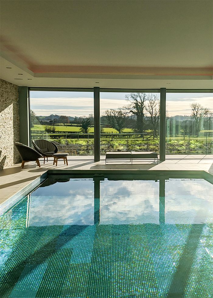 A photo looking down the length of the pool to the glazing and fields beyond.