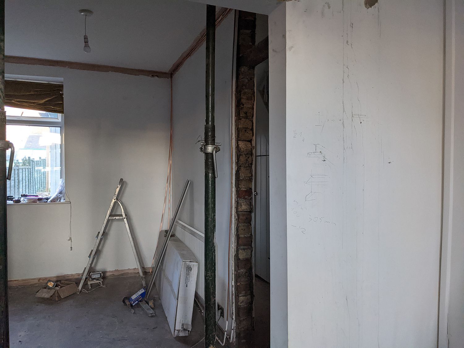 A photo of the area before the desk was built, with bare brick and a radiator along that wall. with