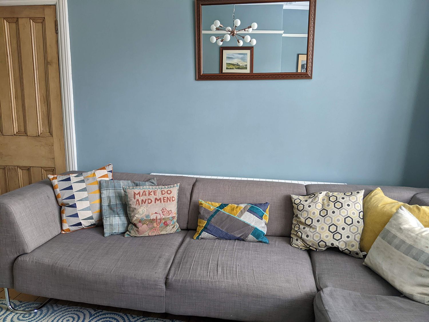 A before photo showing the worn our grey sofa in front of blue grey walls.