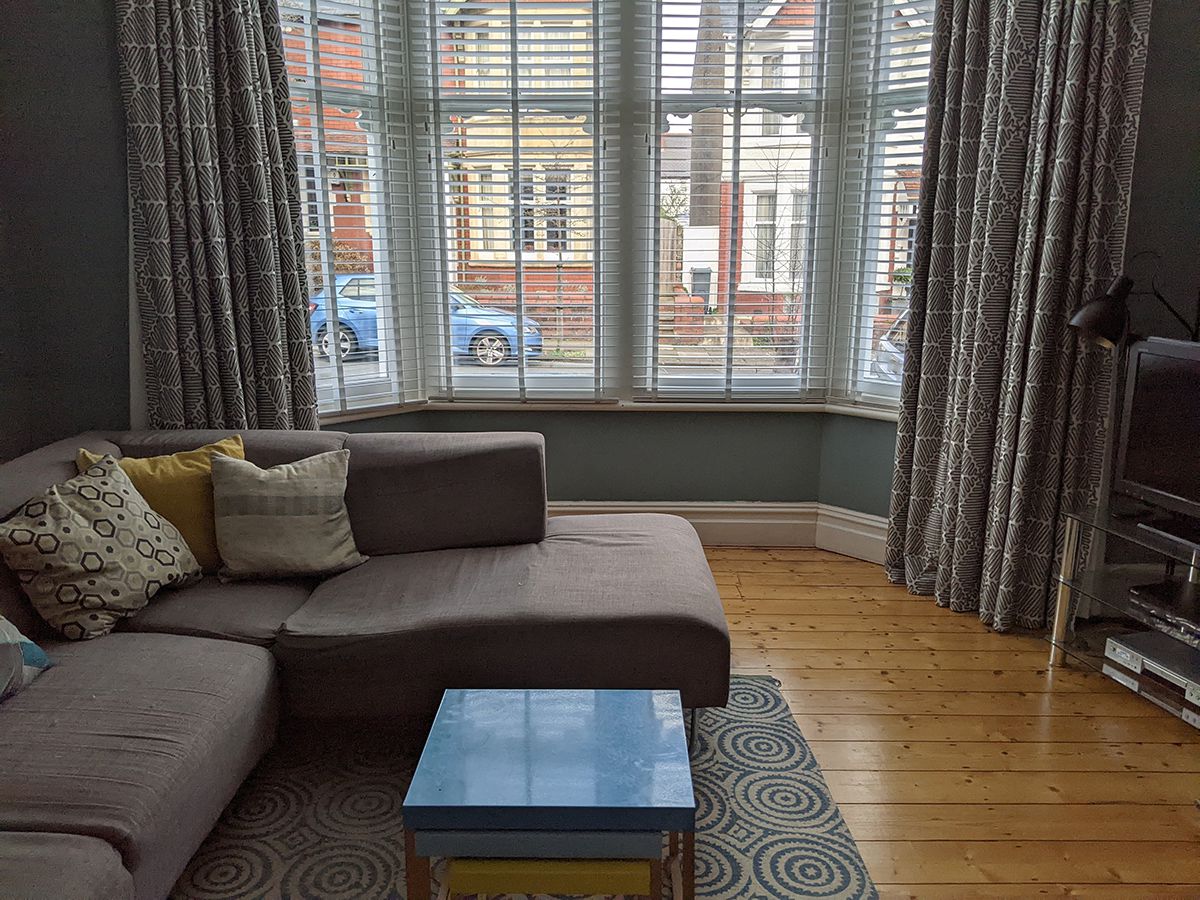 A before photo showing the grey sofa where the chaise now is, with the bay window behind.