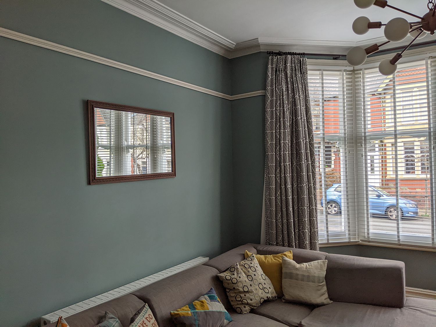 A photo showing the room before, with a grey sofa and grey blue walls.